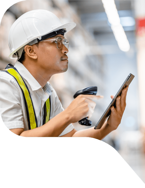 A warehouse worker in a hardhat using a hand-held scanner and a tablet.