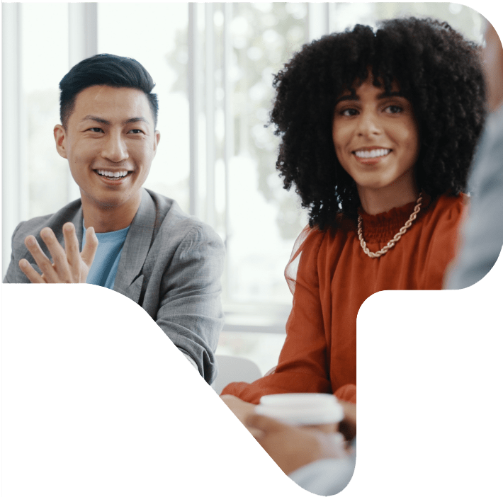 Two smiling people sitting in an office at a meeting.