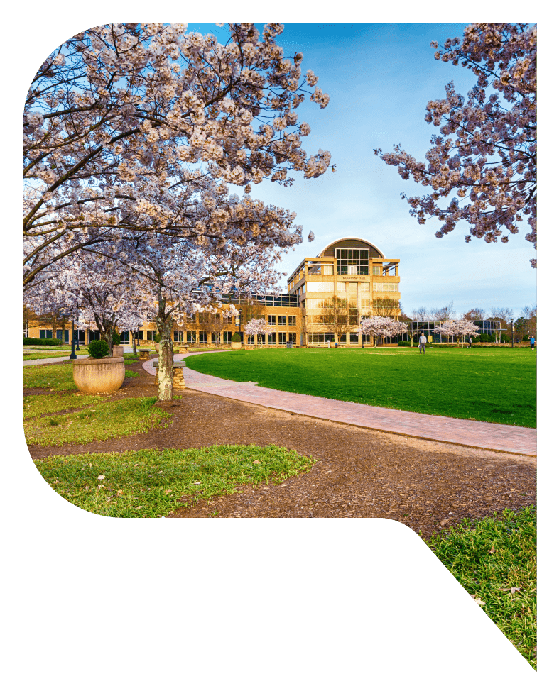 Kennesaw Hall at Kennesaw State University overlooks a green lawn with blooming trees in the foreground in Kennesaw, Georgia.