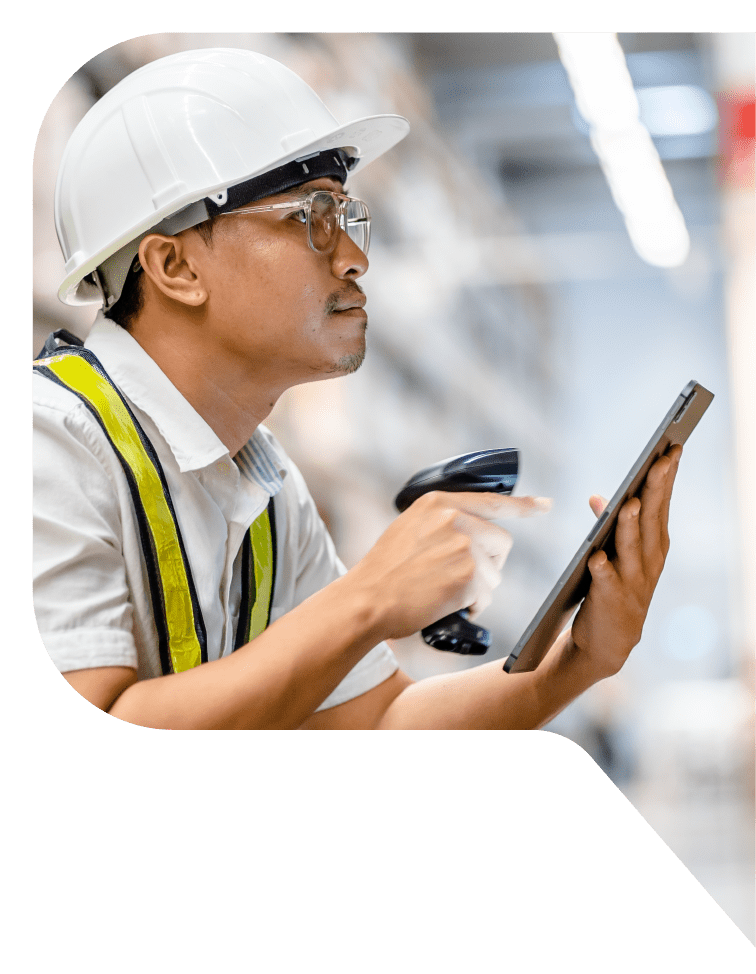 A warehouse worker in a hardhat using a hand-held scanner and a tablet.