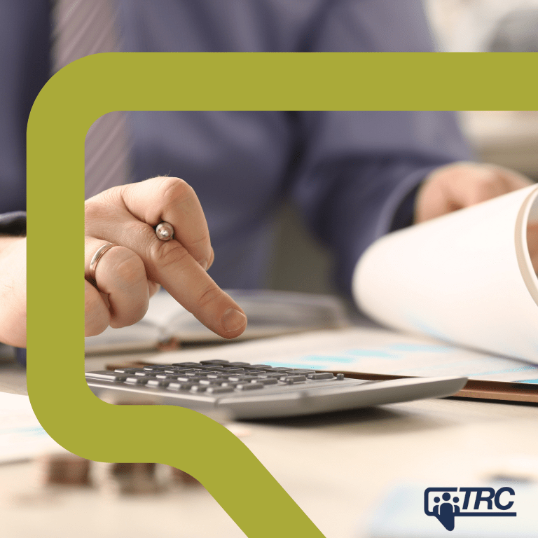 Close up of a hand using a calculator while a person reviews a document.
