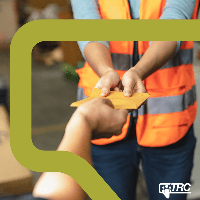 Close up on the hands of a warehouse worker handing an envelope to another person.