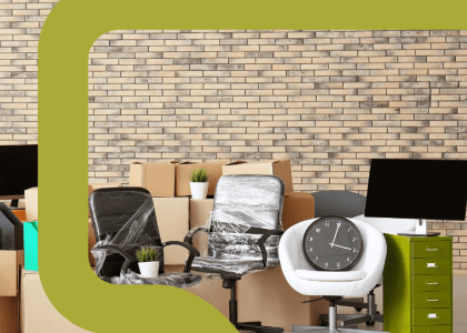 A large room with office equipment and unpacked boxes in front of a brick wall.
