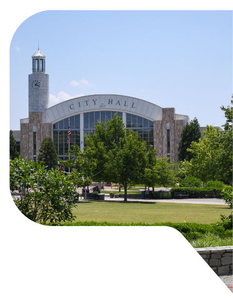 Suwanee, Georgia city hall and the park in front of it under a blue sky.
