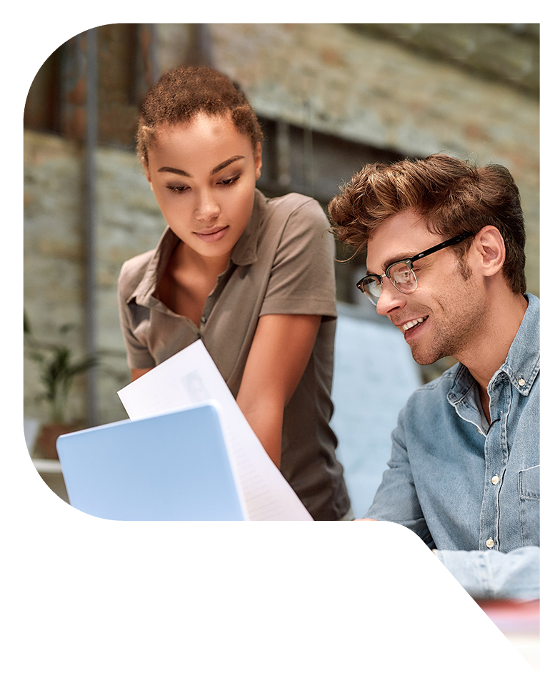 A woman and a man review a document in front of a laptop.