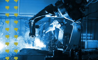 Industrial robotic arms welding metal parts on a production line with bright sparks flying.